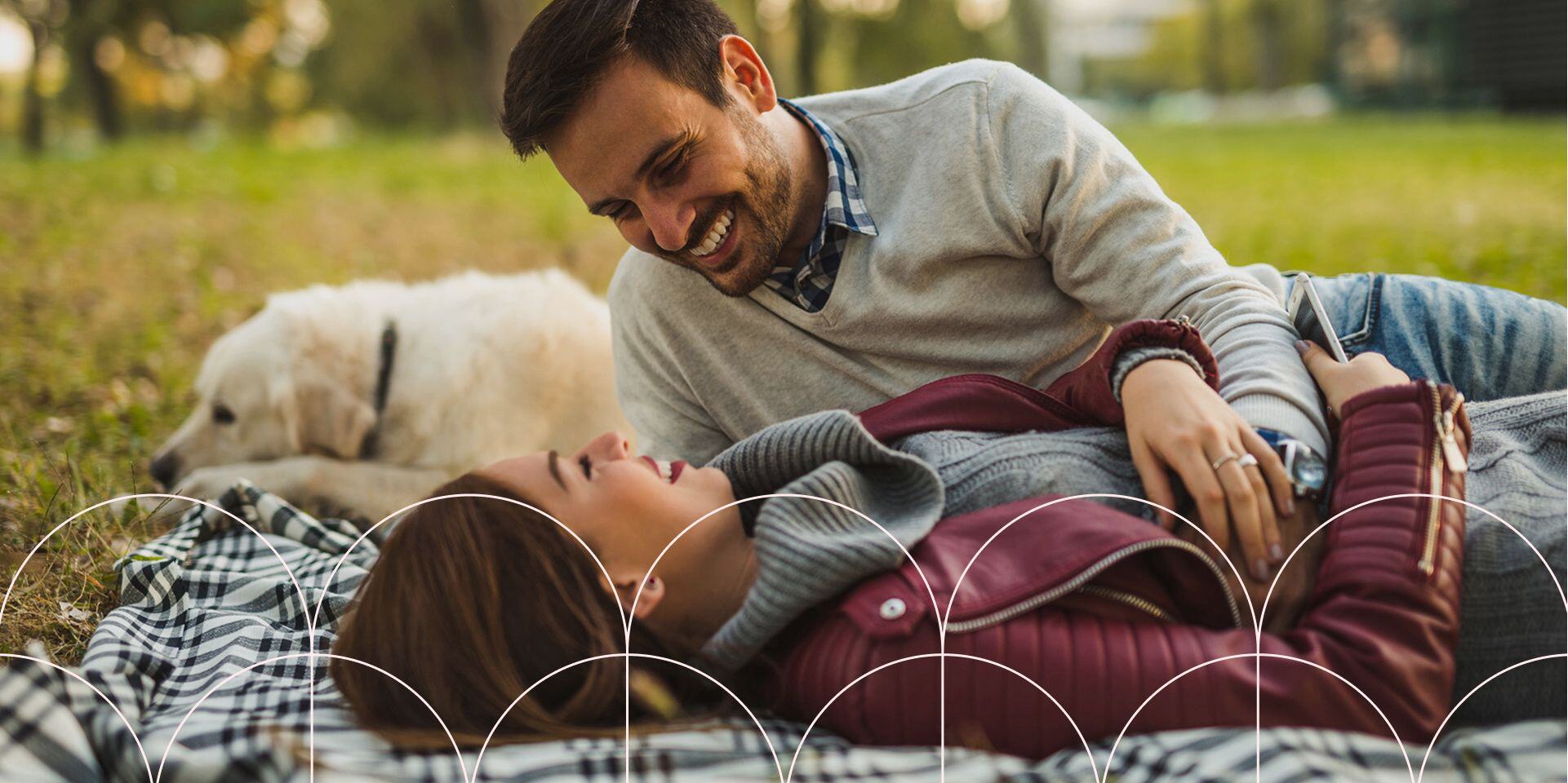 couple with dog on picnic blanket at park