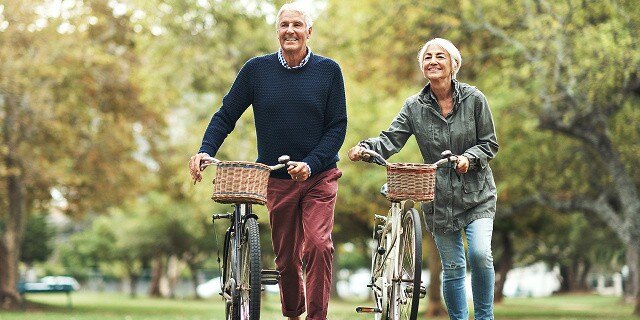 mature couple walking bikes in park